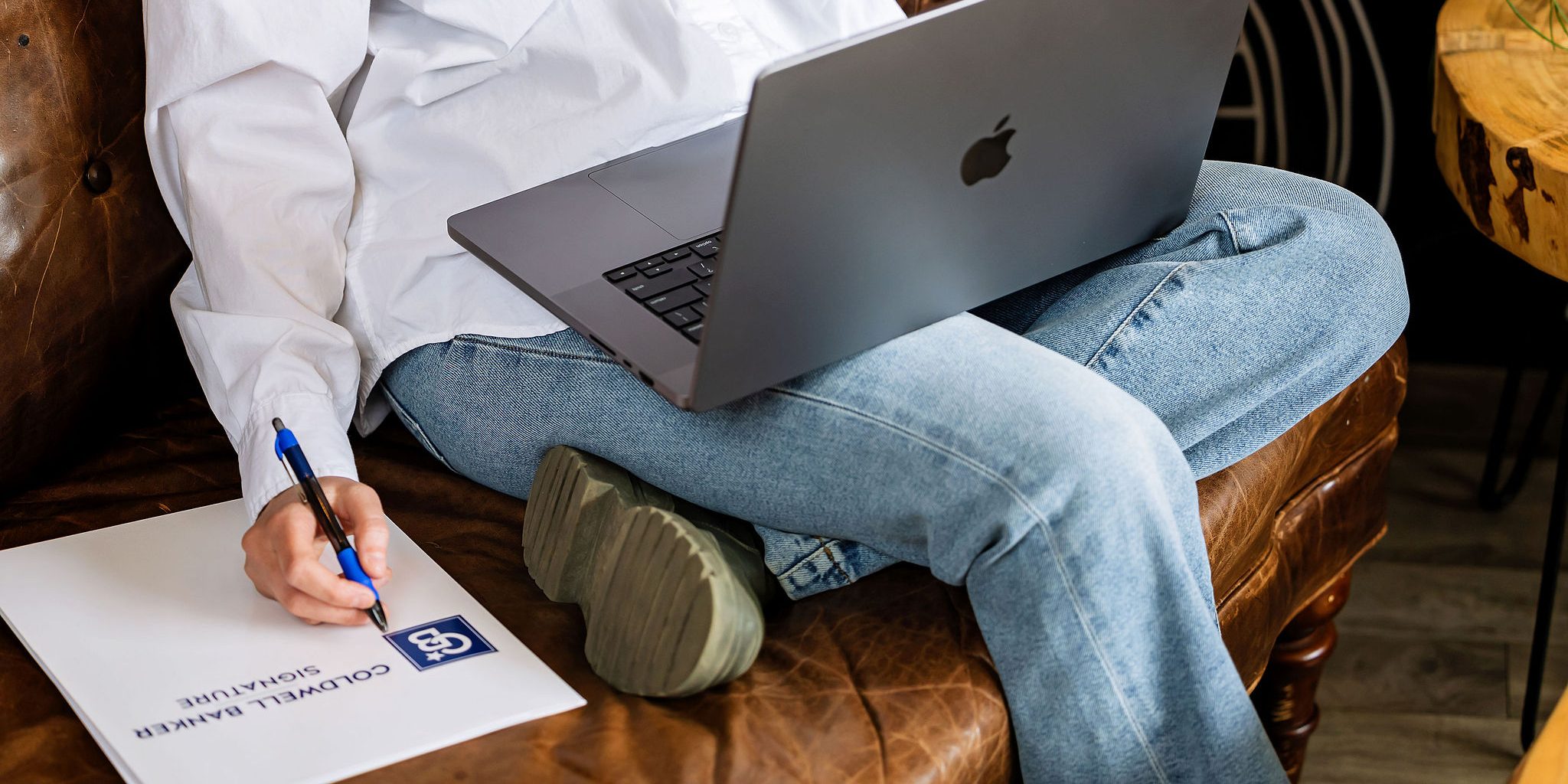 A person filling out a form beside an open laptop