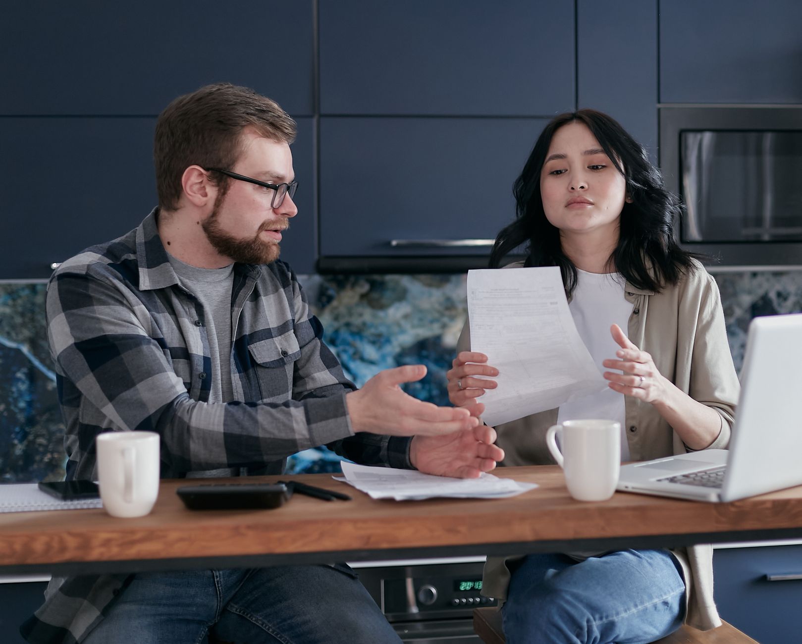 A couple reviewing homebuying paperwork at a kitchen table